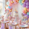 Unicorn party kit styled table with rainbow balloon arch and cake